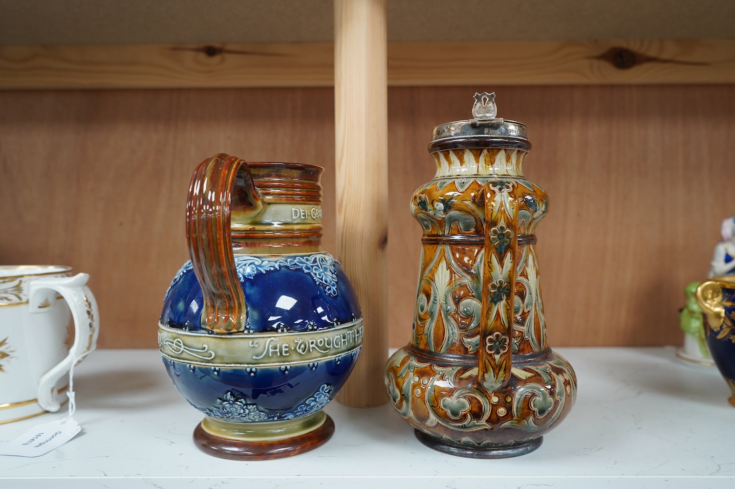 A Doulton Lambeth silver mounted stoneware jug, the silver mount, London 1891, and a Doulton Lambeth Queen Victoria Diamond Jubilee jug, silver mounted jug 21cm high (2). Condition - silver mounting dented